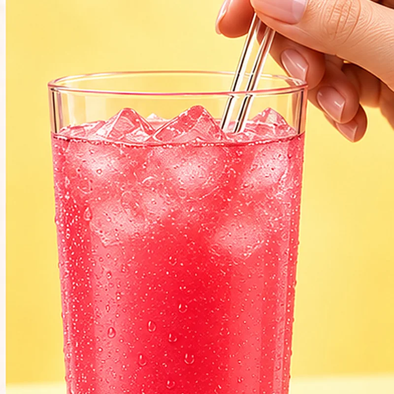 The mixed drink in a tall glass with a straw.