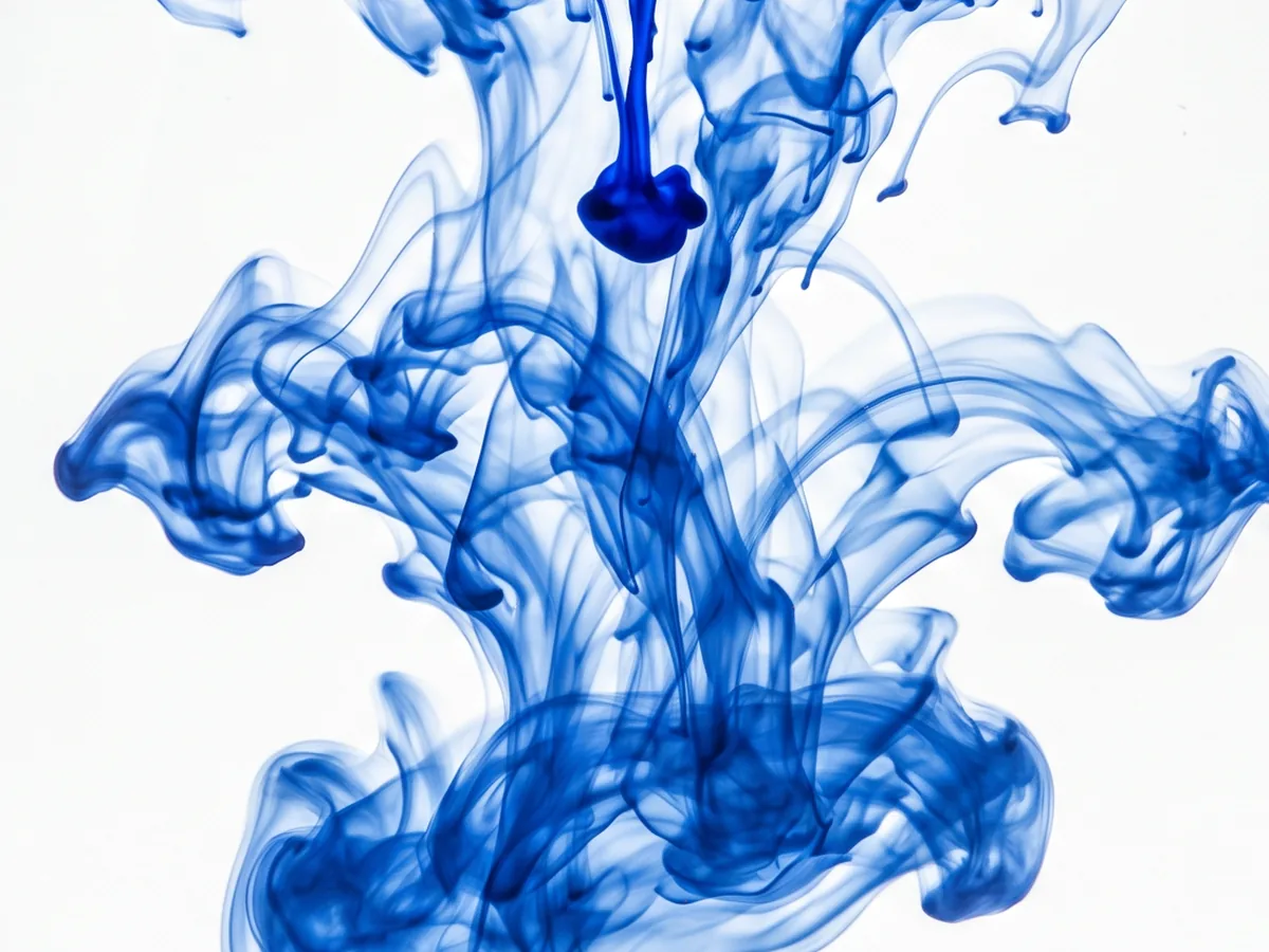 A drop of deep-blue methylene blue blooming into clear water