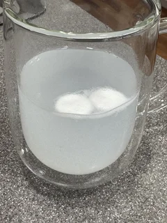 Hydrogen tablet dissolving into a cloudy white solution in a glass of water