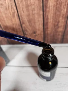 Dropper releasing Methylene Blue solution into the bottle on a wooden surface