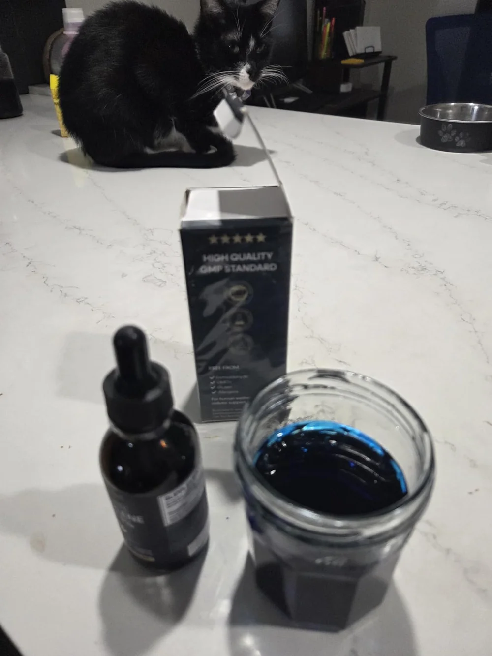 Thriviom Methylene Blue 1% dropper bottle and box on a kitchen counter beside a glass of the diluted blue solution