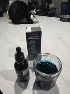 Thriviom Methylene Blue 1% dropper bottle and box on a kitchen counter beside a glass of the diluted blue solution
